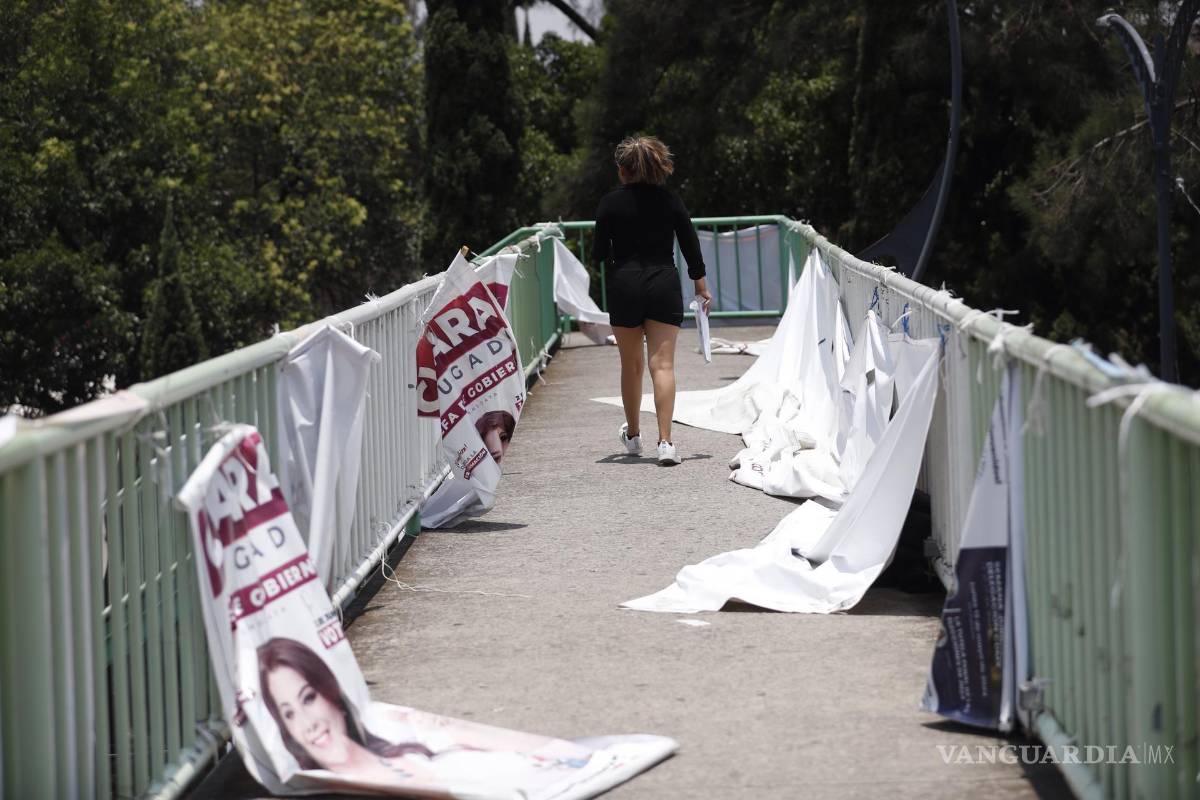 $!Un mujer camina junto a carteles de propaganda electoral en la Ciudad de México (México).