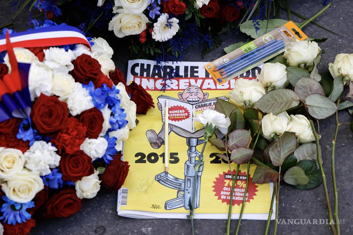 $!Una edición especial del periódico satírico francés Charlie Hebdo entre coronas de flores y lápices dejados frente a las antiguas oficinas de Charlie Hebdo.