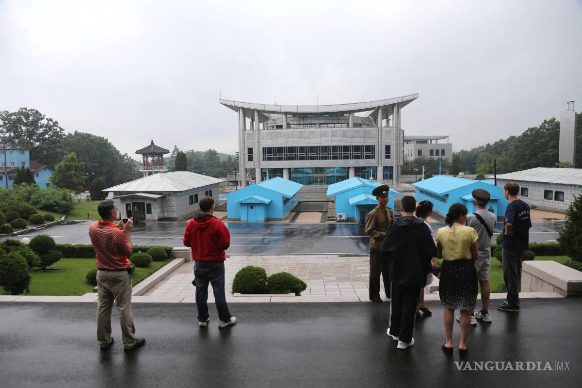 $!Turistas miran hacia un edificio de Corea del Sur mientras los soldados norcoreanos custodian la aldea de Panmunjom en la Zona Desmilitarizada.