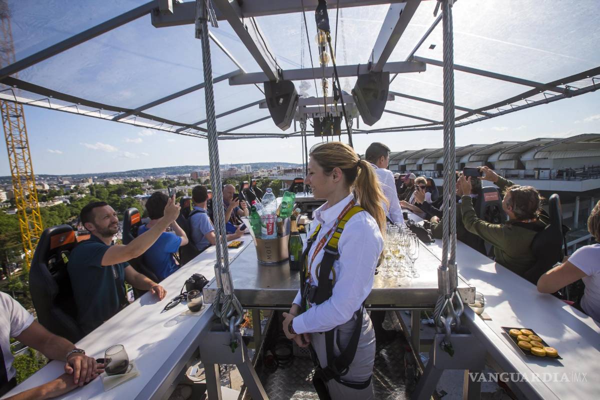 $!Periodistas e invitados asisten a una presentación para la prensa de un bar-restaurante suspendido en una góndola sobre el estadio Roland Garros en París.