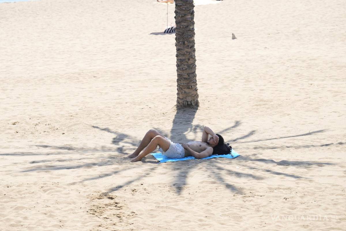 $!Un bañista se protege de la calor, una playa de Barcelona. Cataluña sigue instalada en el calor extremo.
