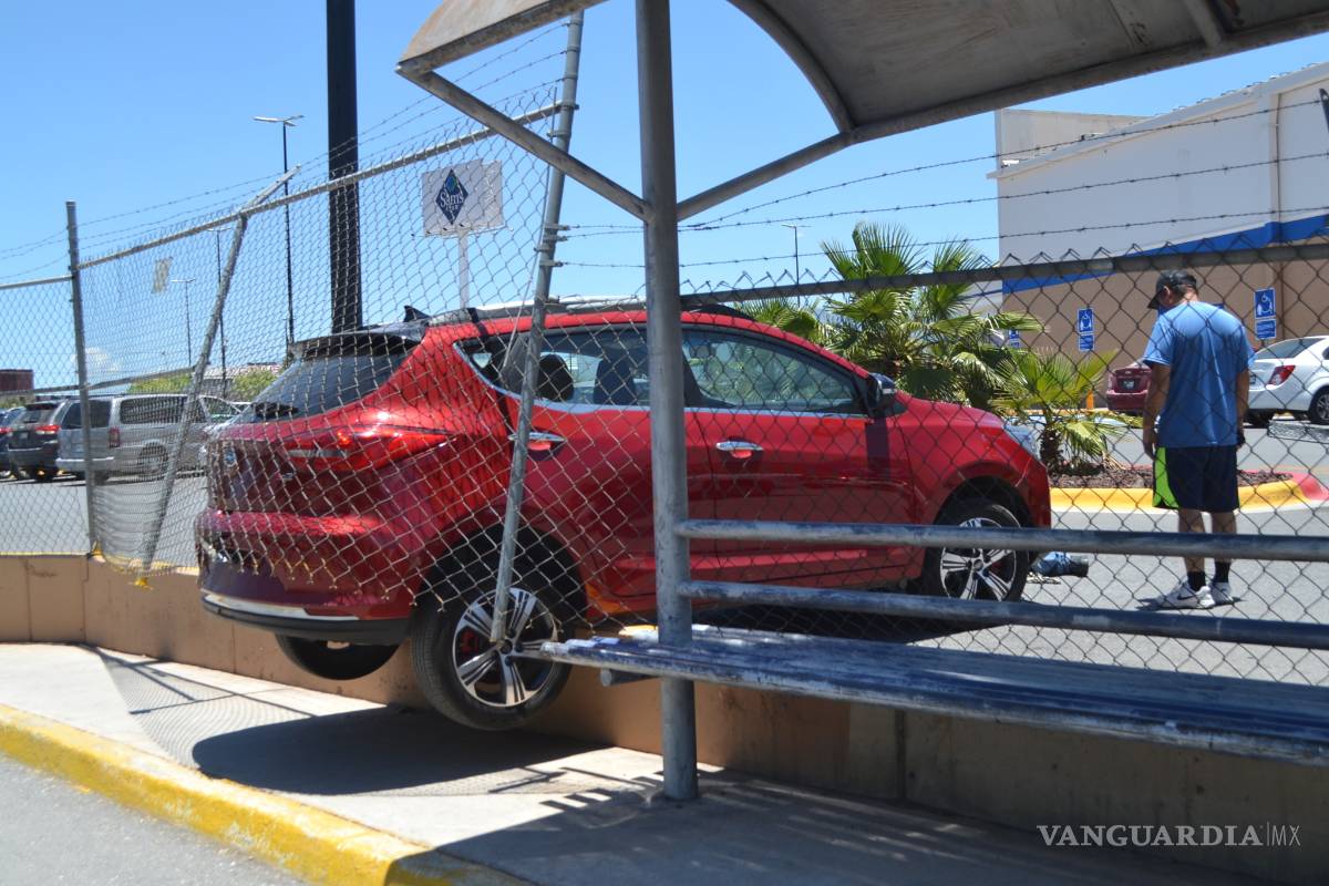 Por error, conductora acelera en reversa y casi se sale de la plaza; valla la detiene