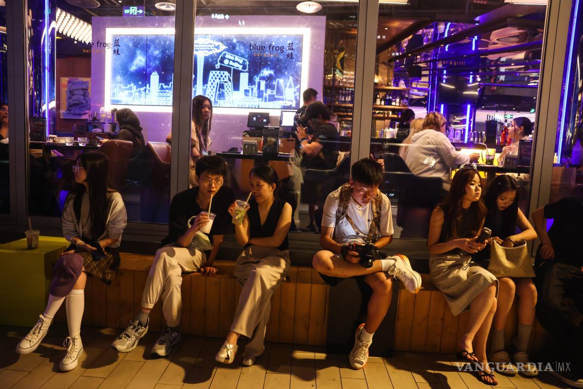 $!Varias personas utilizan sus teléfonos móviles en una plataforma de observación en el Distrito Central de Negocios (CBD) de Pekín, China.