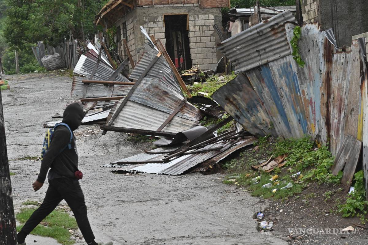$!Una persona camina frente a una casa afectada por el paso del huracán Melissa en Kingston, Jamaica.
