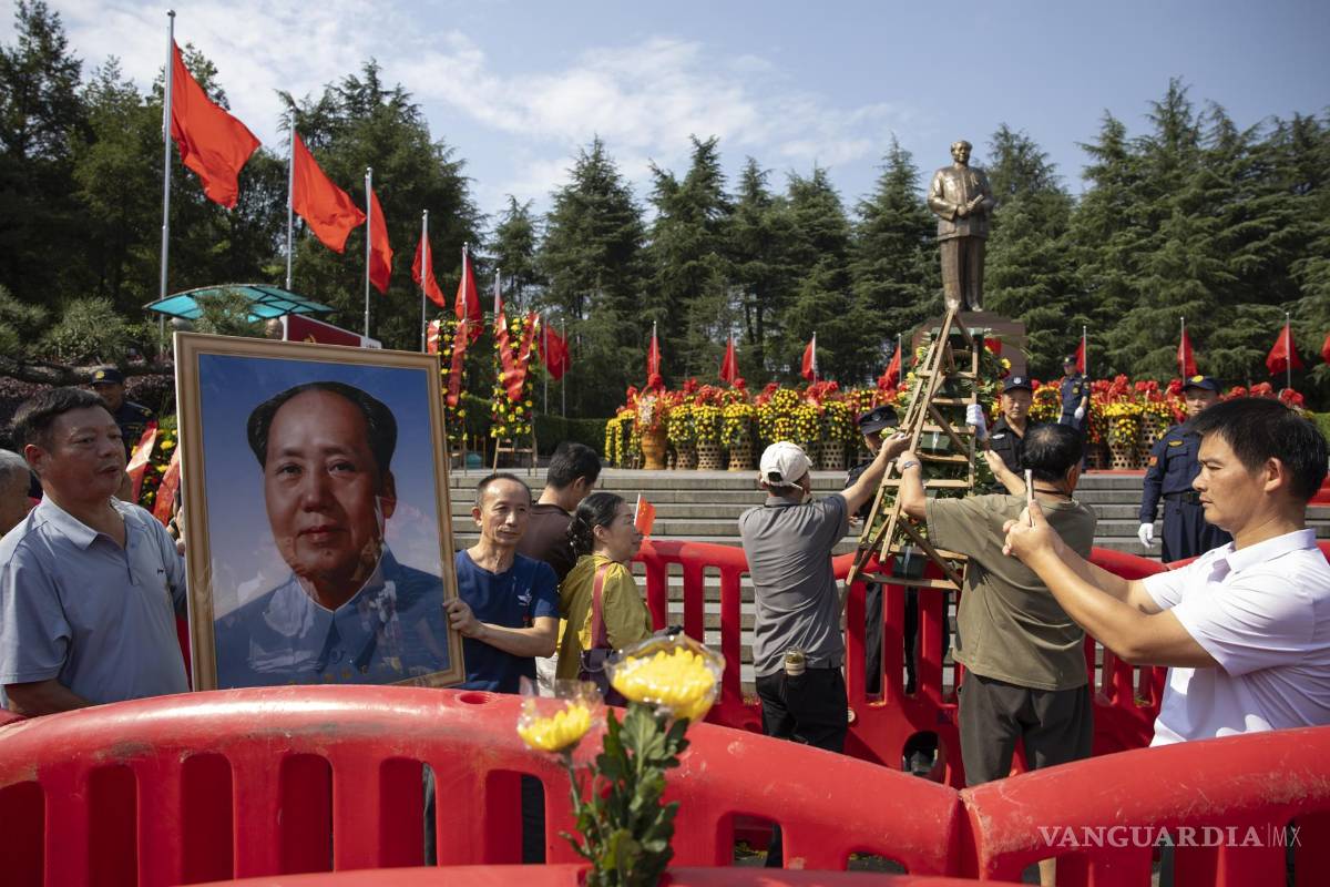 $!Dos personas con un retrato de Mao Zedong durante las conmemoraciones del 50.º aniversario de su muerte en Shaoshan, provincia de Hunan, en el centro de China.