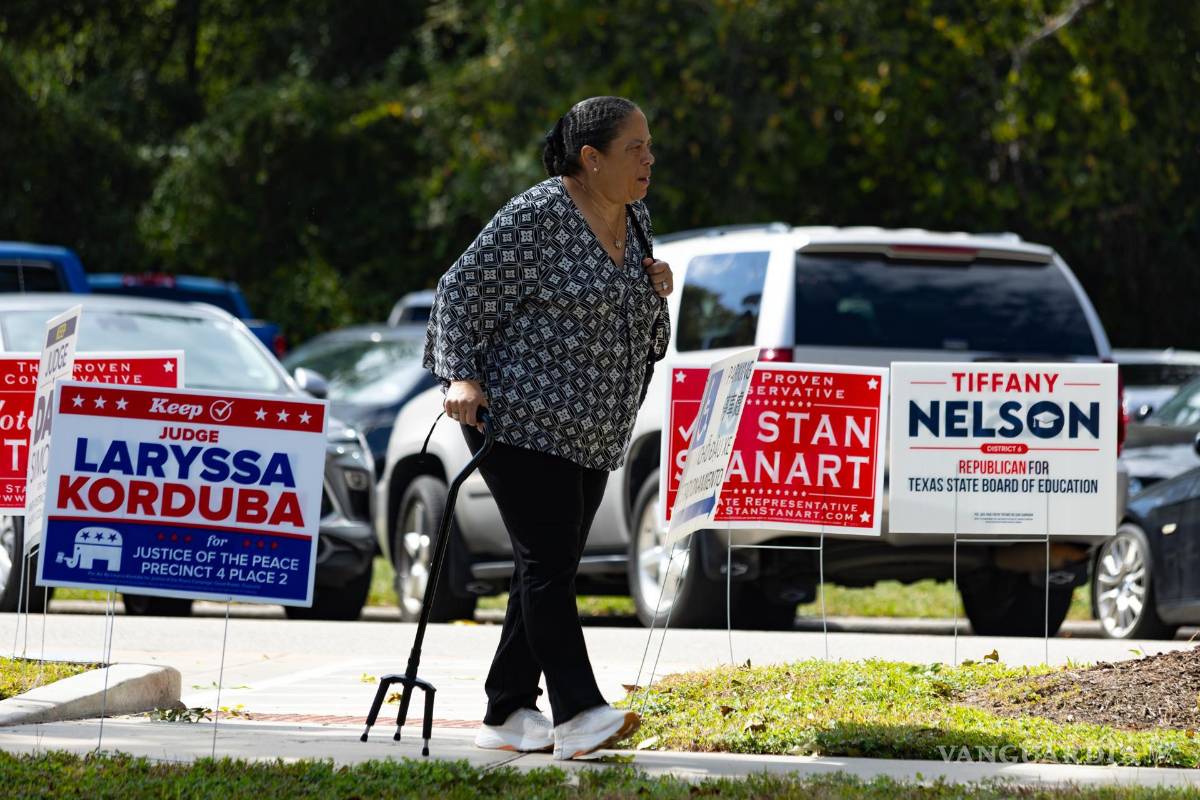 $!Una mujer camina junto a publicidad electoral durante la jornada de votación anticipada este lunes, en el centro George Bush en Houston, Texas.