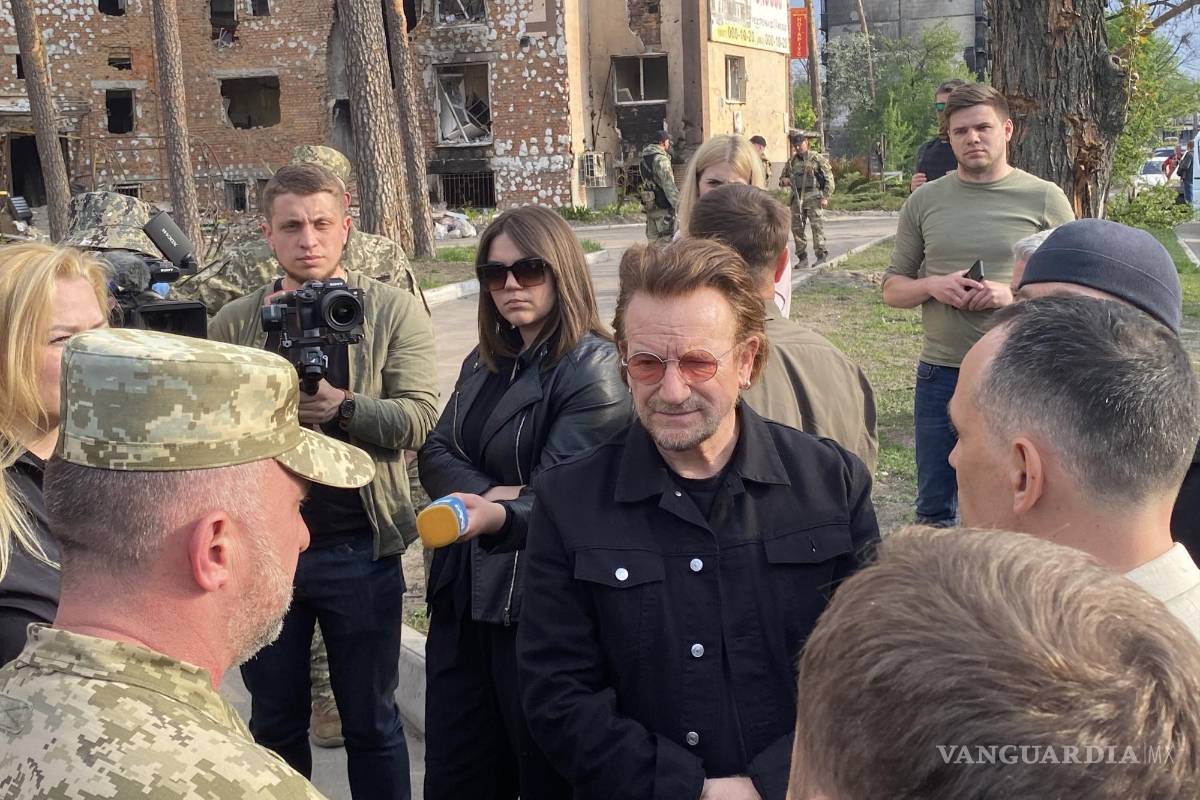 $!El músico irlandés de la banda U2, Bono (c), durante su visita este domingo en la localidad ucraniana de Irpin.