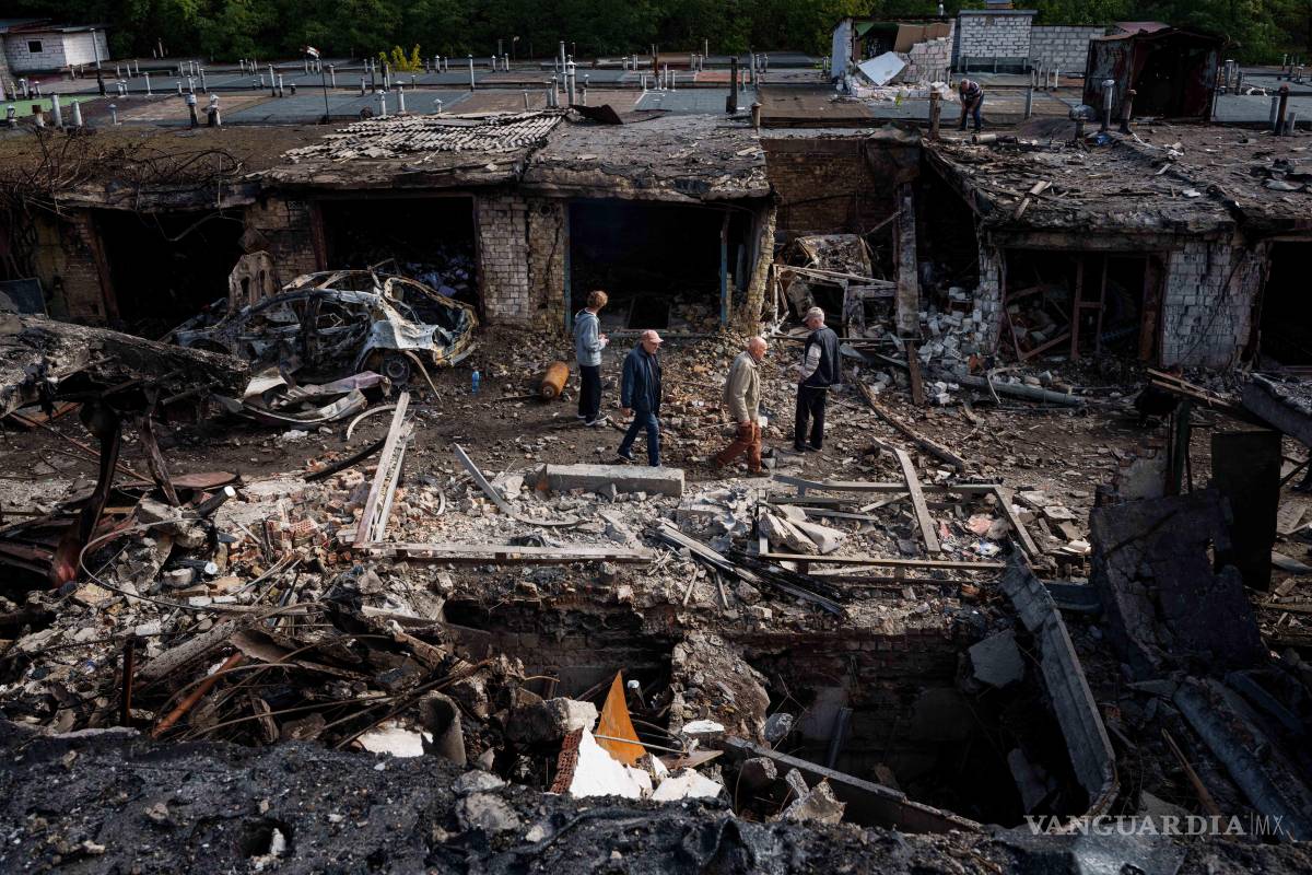 $!Personas caminan frente a garajes destruidos en un ataque con misiles rusos en Vyshhorod, en la región de Kiev, Ucrania.