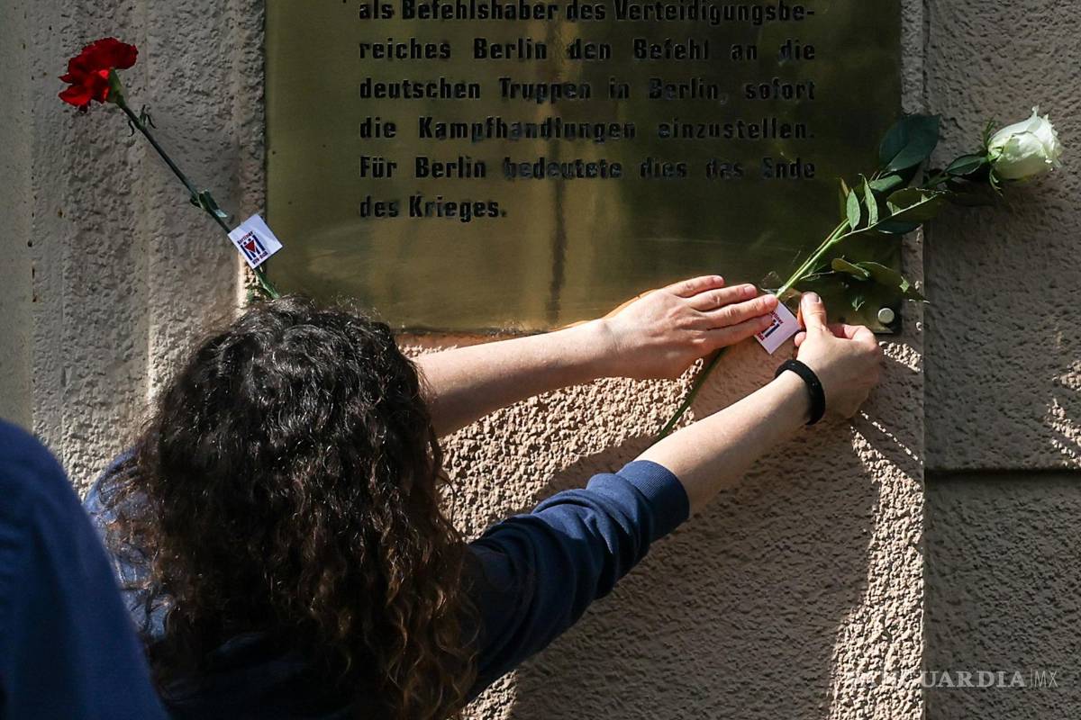$!Una mujer coloca una flor en la fachada de una casa en el sitio histórico de la Capitulación de Berlín, en la calle Schulenburgring en Berlín, Alemania.