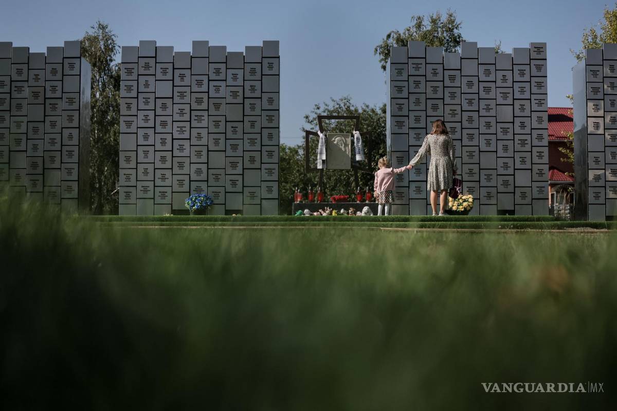 $!Una mamá con su hija visitan un monumento conmemorativo con los nombres de 501 personas identificadas víctimas de crímenes de guerra, en Bucha, Ucrania.