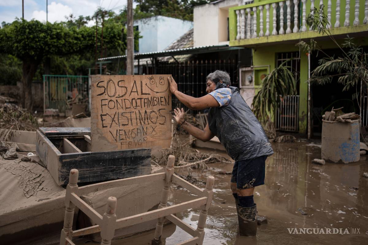 $!Una mujer alza un cartel que dice “SOS. En el fondo también existimos. Por favor, vengan”, en Poza Rica, Veracruz, México las tras inundaciones.