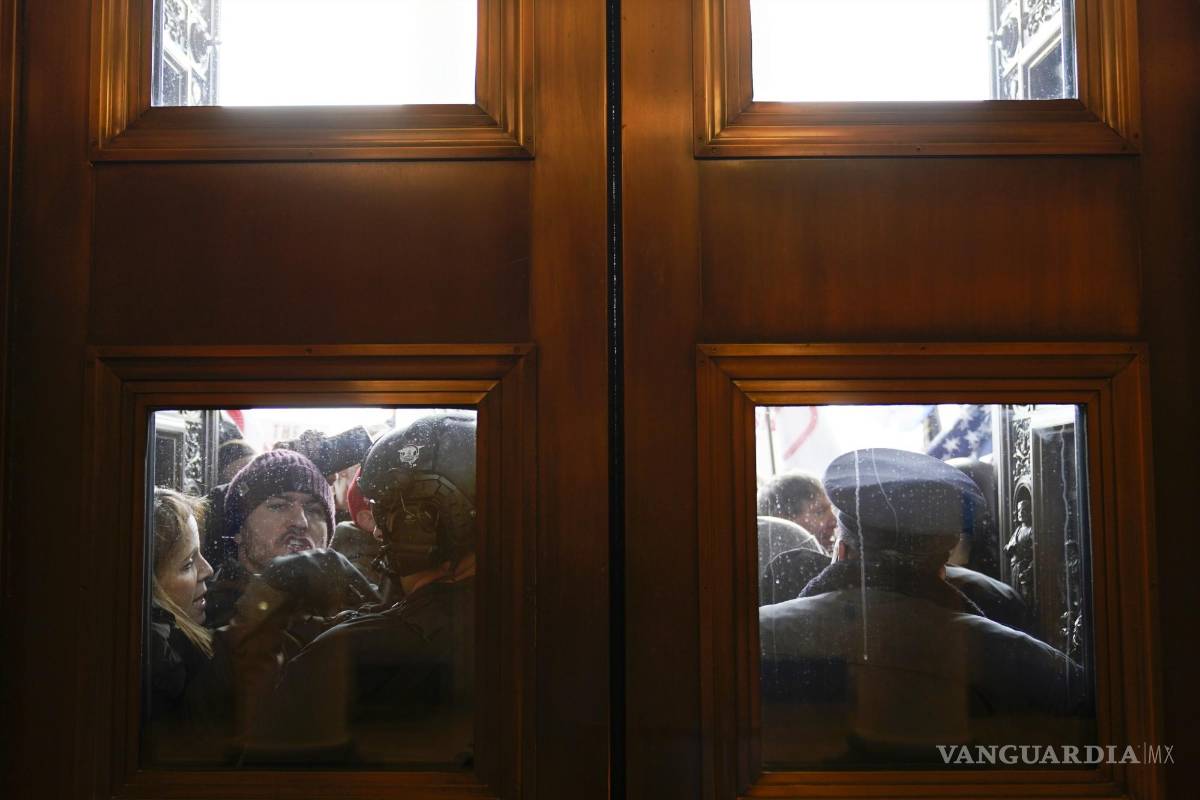 $!La Policía del Capitolio intenta contener a los alborotadores fuera de las puertas de la Cámara del Capitolio el 6 de enero de 2021. AP/Andrew Harnik
