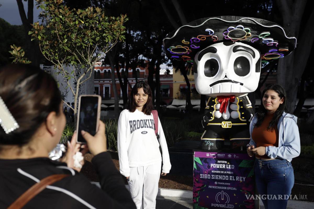 $!Personas se toman fotografías con piezas de la exposición Me lleva la huesuda en el zócalo de la ciudad de Puebla (México).