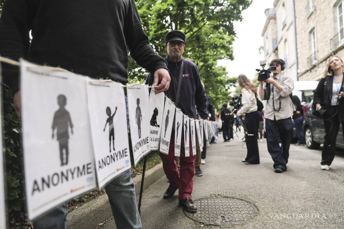 $!Personas, incluidas víctimas, portan pancartas que representan a las víctimas de Joel Le Scouarnec en el día del veredicto del juicio del cirujano francés en Vannes.