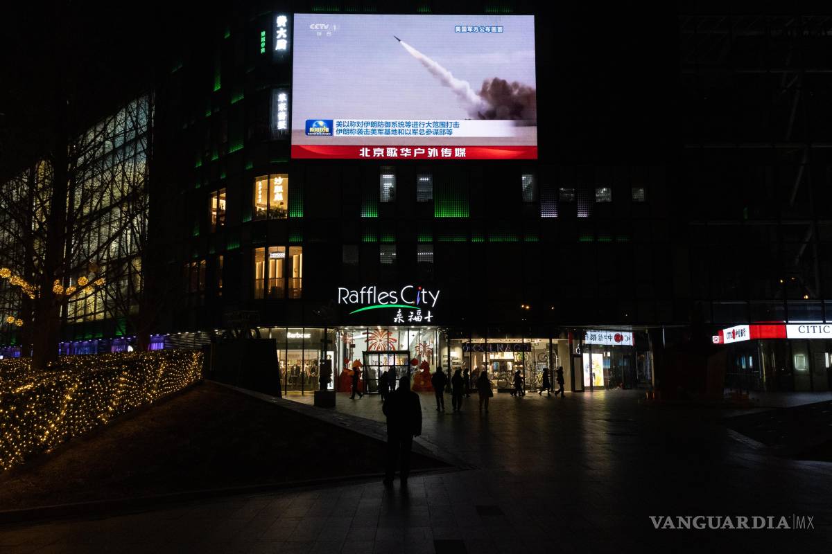 $!Personas observan una transmisión en una pantalla en un centro comercial sobre los ataques estadounidenses e israelíes en Irán y el contraataque iraní, en Pekín.