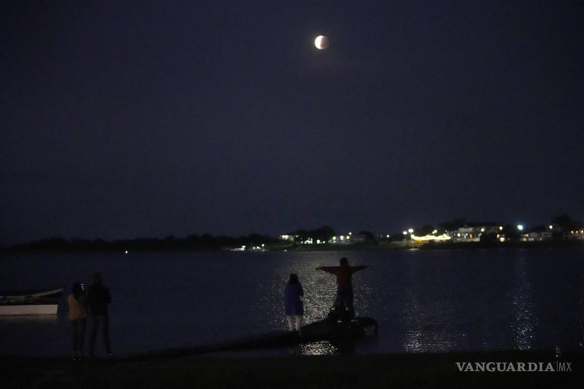 $!La gente se reúne para ver la luna parcialmente eclipsada que se asienta sobre el río Paraguay en Asunción, Paraguay. AP/Jorge Saenz