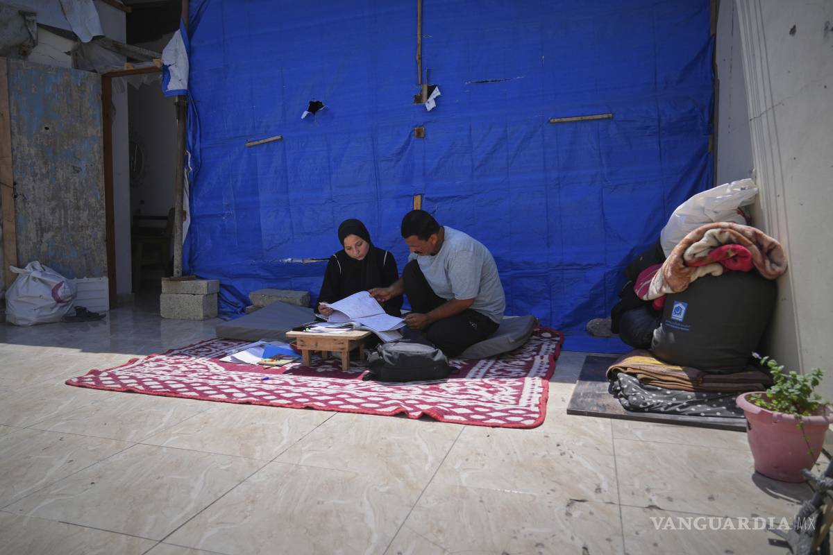 $!Sarah Qanan estudia con su padre, Ibrahim, en la tienda de campaña de su familia en Khan Younis, Franja de Gaza.