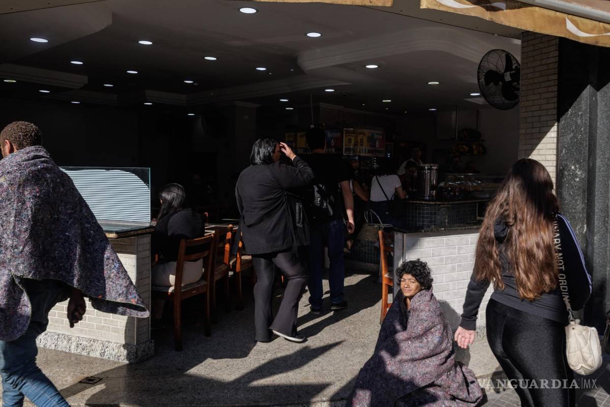 $!Una persona en situación de calle descansa frente a un restaurante en el centro de la ciudad, en Sao Paulo, Brasil.