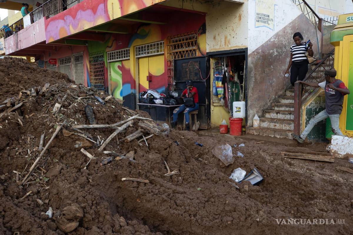 $!Personas caminan por el lodo en una calle afectada por el paso del huracán Melissa en Santa Cruz, Jamaica.