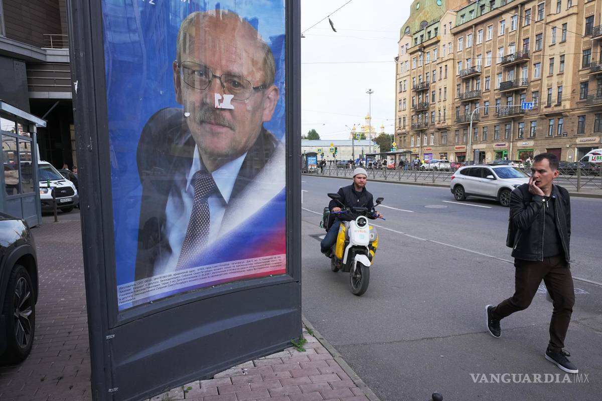 $!Unas personas pasan junto a una valla publicitaria que invita a votar por el candidato del partido Rusia Unida al parlamento local en San Petersburgo.