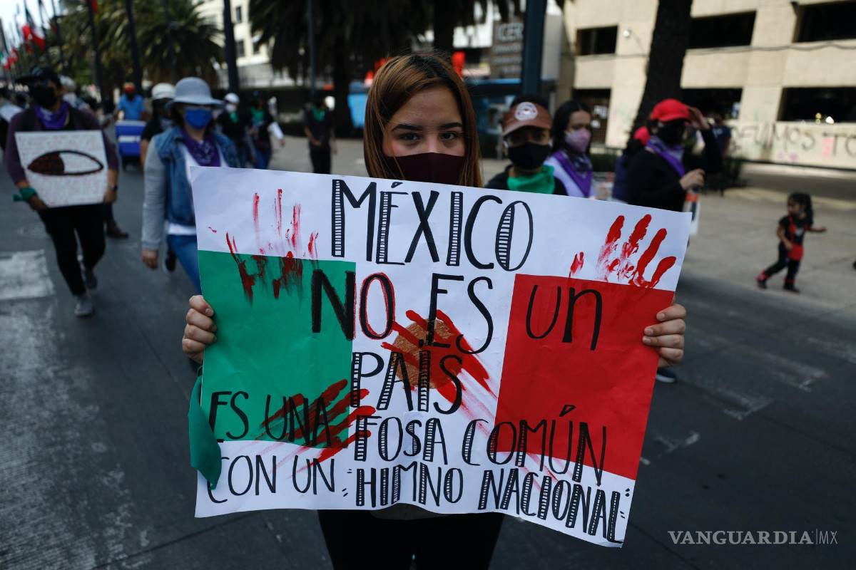 $!8/03/2021. Una manifestante con un cartel con la frase México no es un país, es una fosa común con un himno nacional durante una marcha en CDMX.