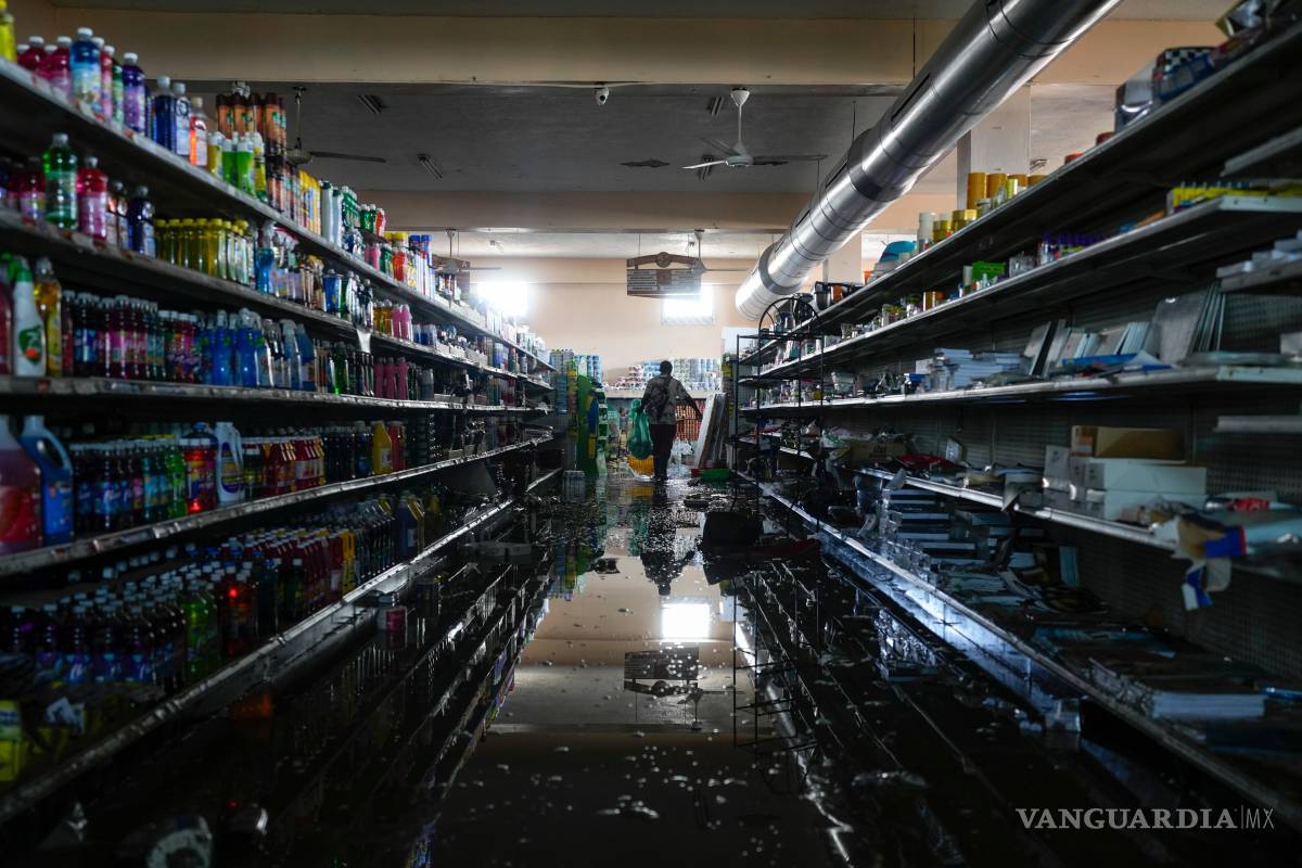 $!Con el permiso del dueño del supermercado, un residente se sirve provisiones y alimentos en Black River, Jamaica tras el paso del huracán Melissa.