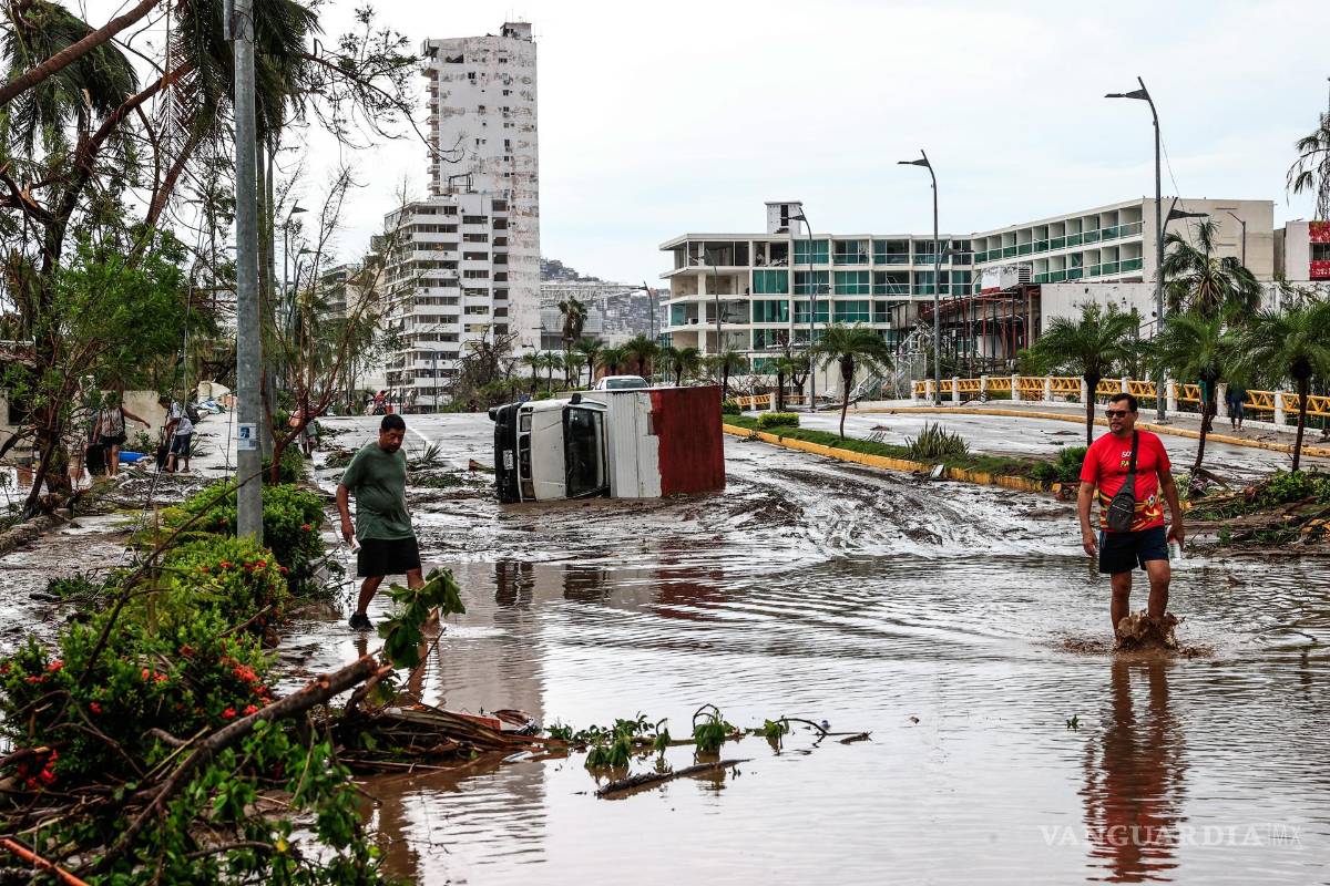 $!Vecinos caminan entre los escombros en una calle inundada por el huracán Otis en el balneario de Acapulco, en el estado de Guerrero, México.