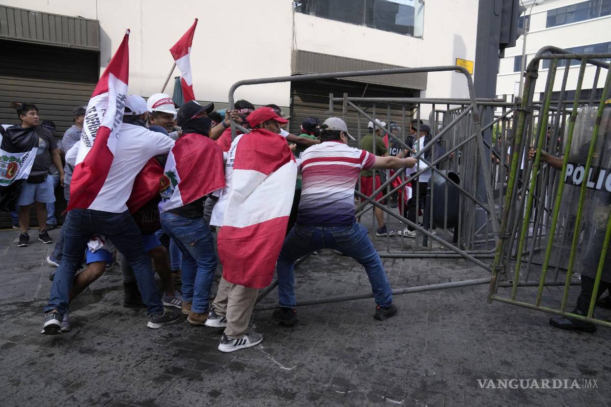 $!Manifestantes opositores que viajaron a la capital para marchar contra la presidenta peruana Dina Boluarte derriban una barricada de la policía.