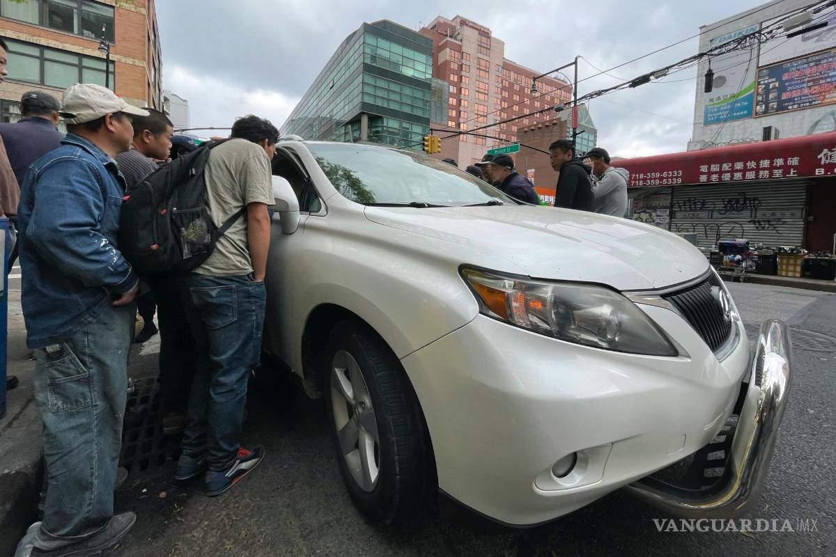 $!Wang Gang, de 36 años, centro izquierda, inmigrante chino, conversa con el conductor de un coche para conseguir un trabajo en el barrio de Flushing.
