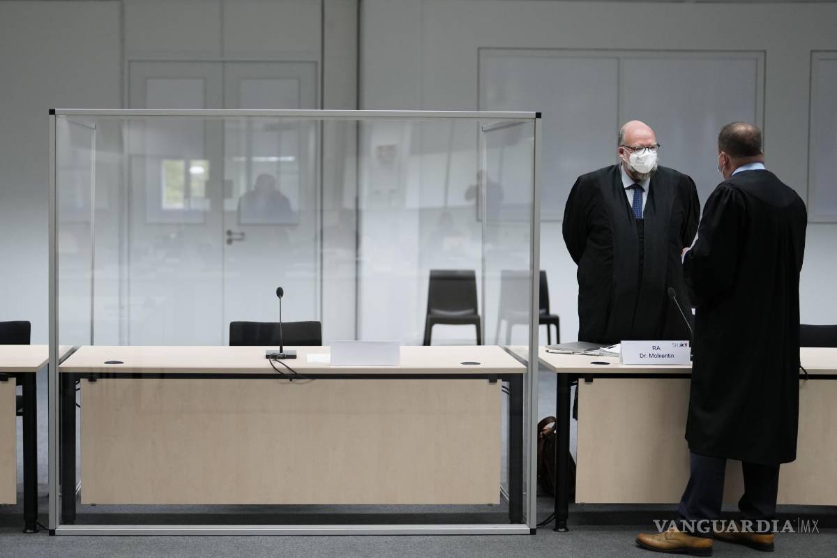 $!Dos legisladores de pie junto a un asiento vacío del acusado en la sala del tribunal, antes de un juicio contra un exsecretario de 96 años del comandante de las SS del campo de concentración de Stutthof en el tribunal de Itzehoe, Alemania. AP/Markus Schreiber