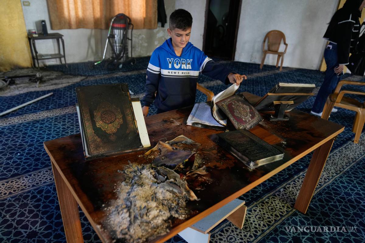 $!Un niño inspecciona copias quemadas del Corán dentro de una mezquita que fue incendiada y profanada por colonos israelíes en la ciudad de Deir Istiya.