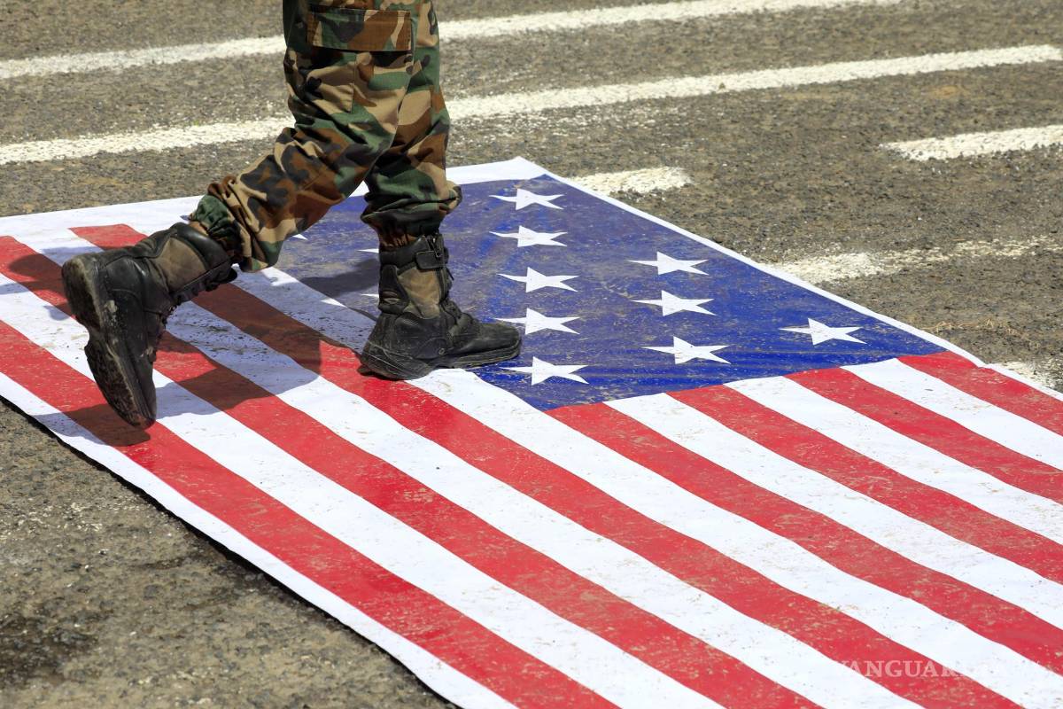 $!Un soldado hutí camina sobre una bandera estadounidense durante una manifestación en apoyo al embargo naval impuesto por los hutíes contra Arabia Saudita en Saná, Yemen.