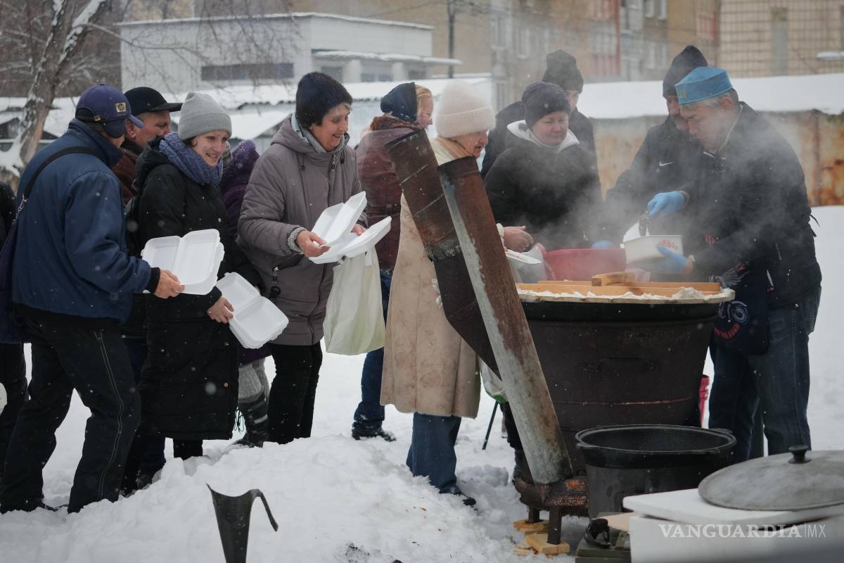 $!El voluntario Marat Darmenov (d) sirve comida caliente gratuita a los residentes de Kiev durante un apagón provocado por los frecuentes ataques aéreos rusos.