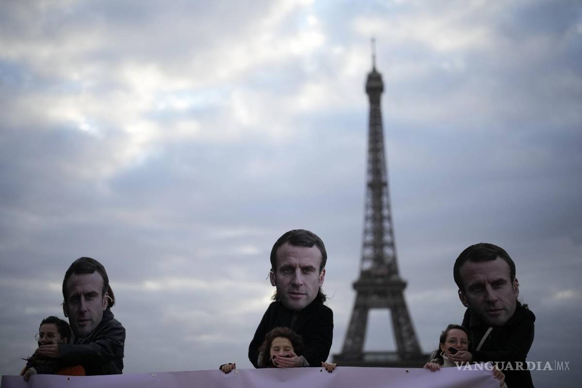 $!Personas con máscaras del presidente francés Emmanuel Macron protestan en París.