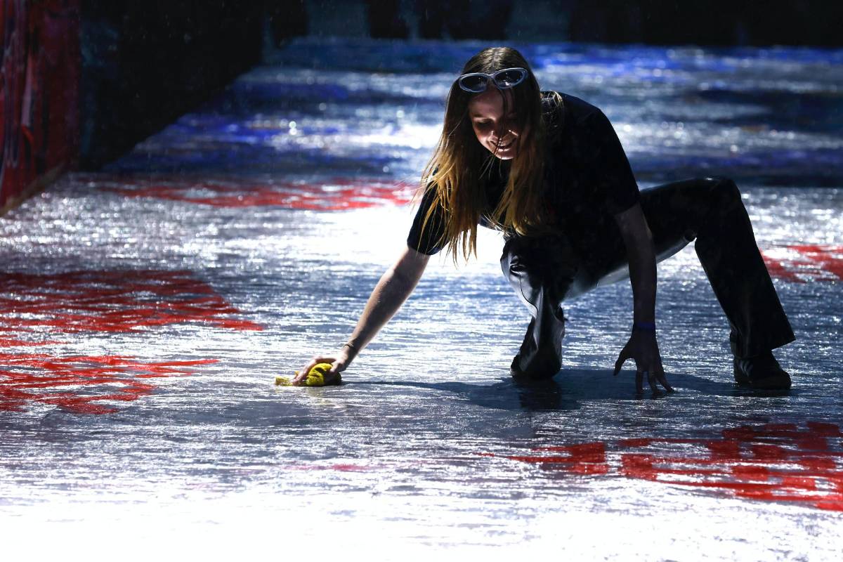 $!Una trabajadora intenta secar la pasarela durante una lluvia antes del desfile de la colección Otoño 2022 de Tommy Hilfiger en la Semana de la Moda en Nueva York.