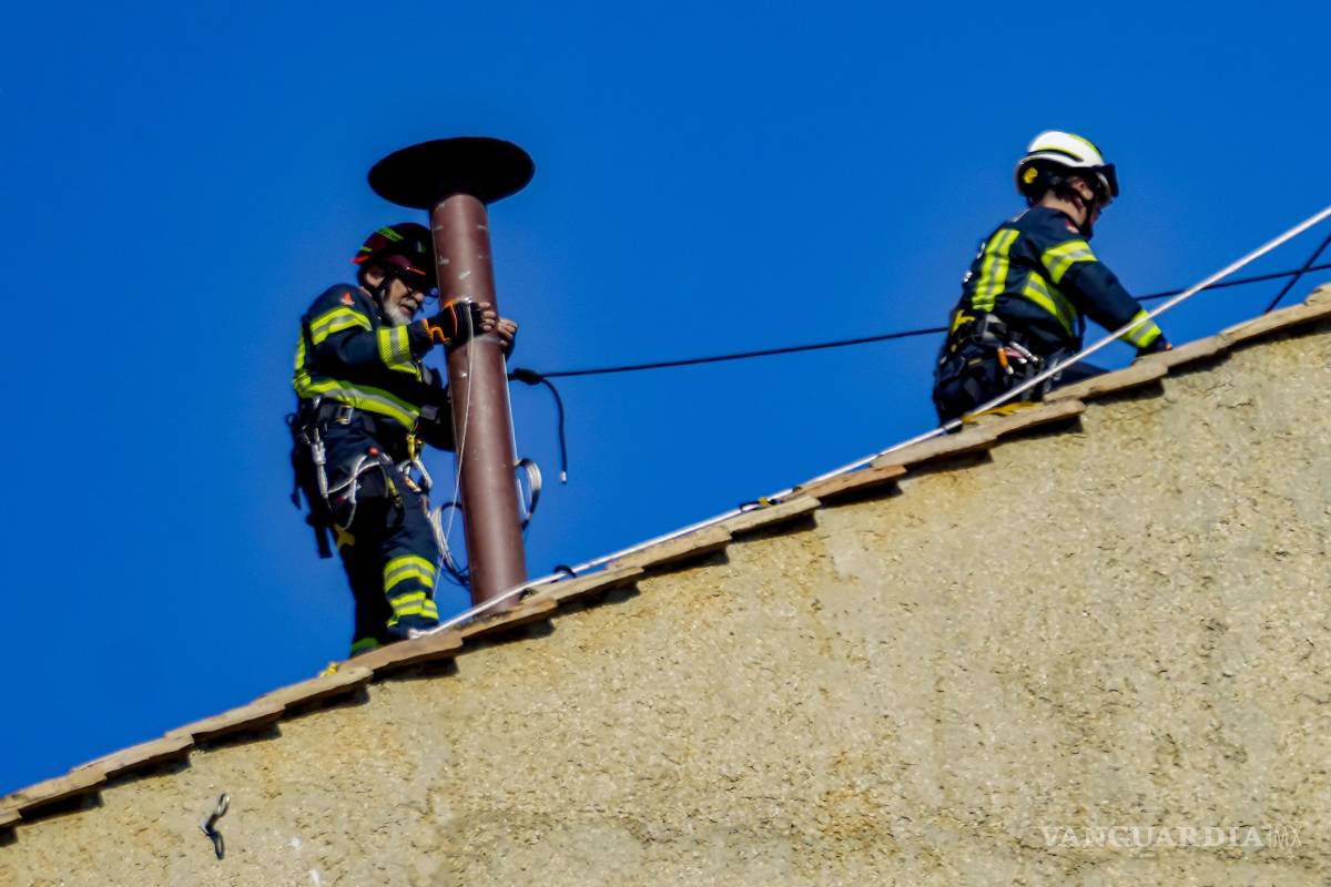 $!Los bomberos colocan la chimenea en el techo de la Capilla Sixtina, donde los cardenales se reunirán para elegir al nuevo papa, en el Vaticano.