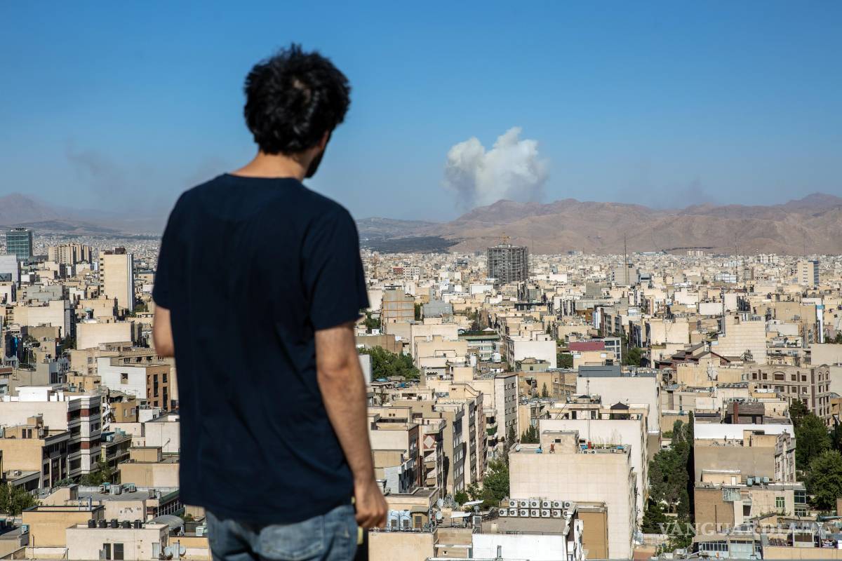 $!Un hombre en Teherán observa cómo se elevan columnas de humo durante un ataque aéreo israelí.