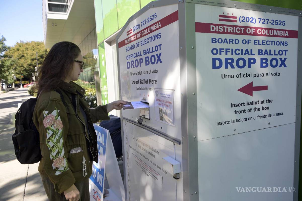 $!Una mujer deposita un sobre con su voto este martes, en una urna oficial de votación en una calle, en Washington.