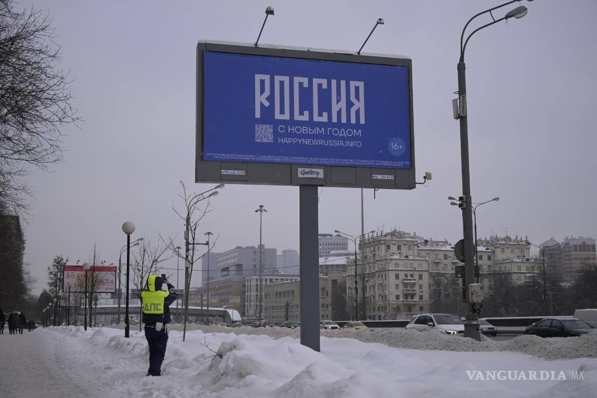 $!Un oficial de la policía de tránsito toma una fotografía de un cartel con las palabras Feliz Año Nuevo y el código QR en Moscú, Rusia.