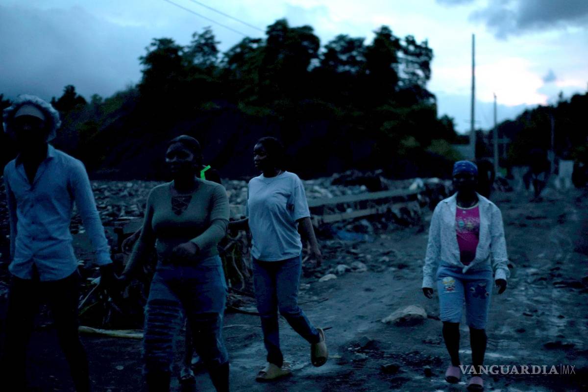 $!Personas caminan sobre el lodo por la creciente del río La Digue este miércoles, en Petit Goave, Haití.