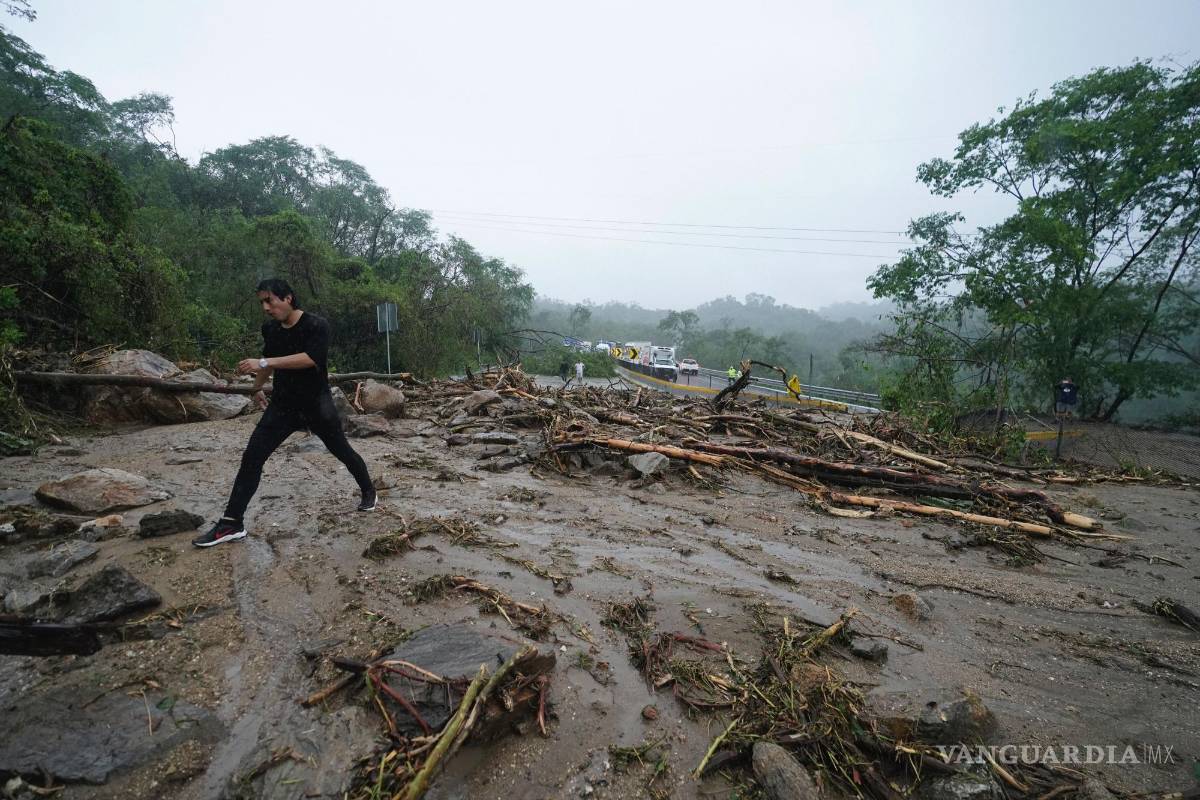 $!Un hombre cruza una carretera bloqueada por un deslizamiento de tierra provocado por el huracán Otis cerca de Acapulco, México.