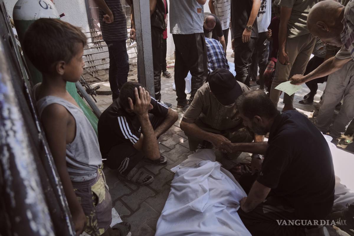 $!Dolientes se reúnen en torno a los cadáveres de los palestinos que murieron al intentar llegar a los camiones de ayuda que ingresan al norte de Gaza.