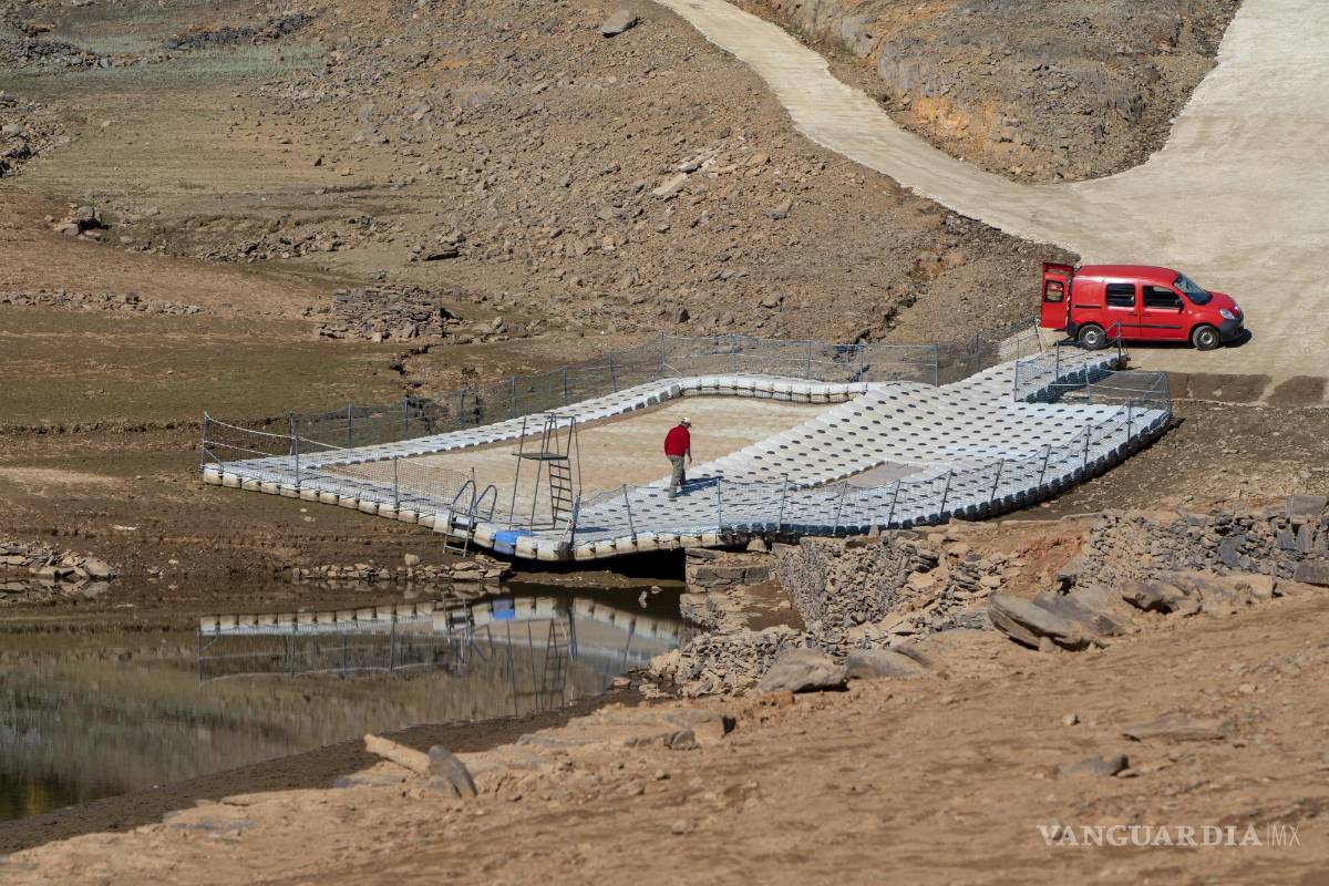 $!Un hombre camina sobre una piscina flotante sobre suelo seco del río Zezere, debido a la sequía, cerca de Pampilhosa da Serra, en el centro de Portugal.