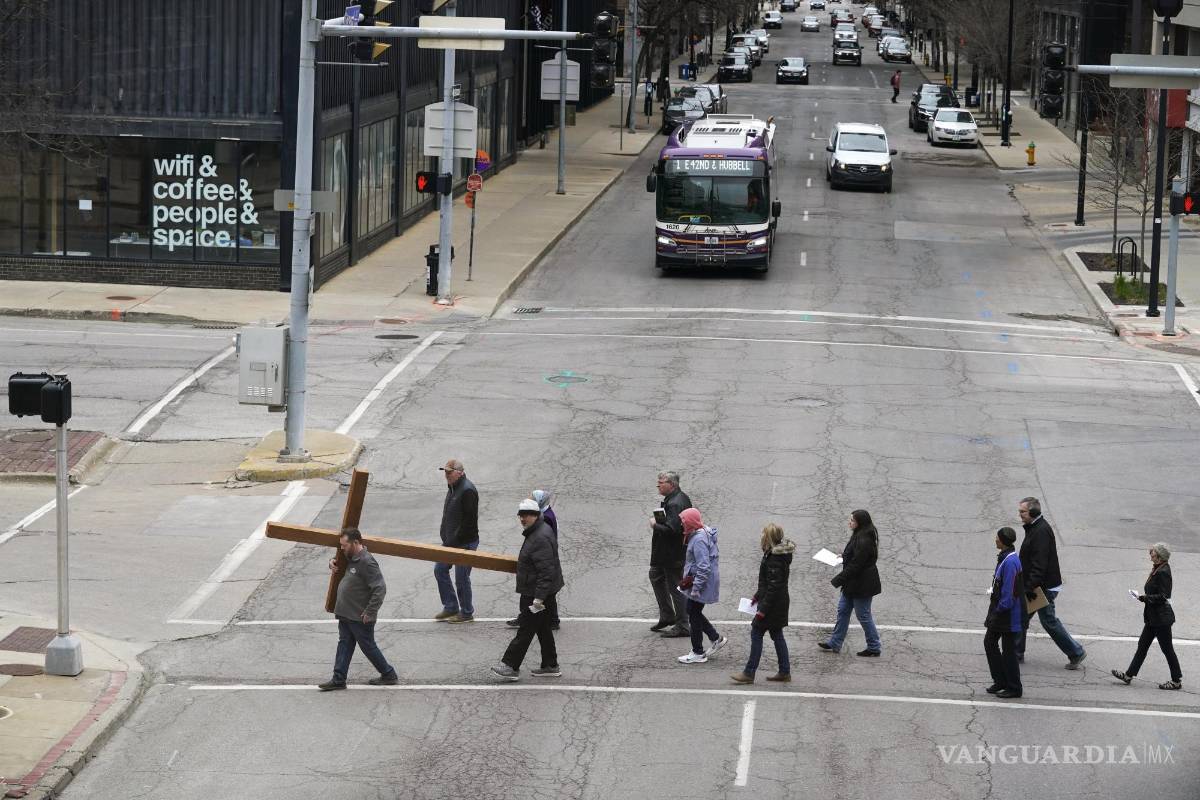 $!Rob Hoover, de Des Moines, Iowa, a la izquierda, lleva una cruz de madera mientras dirige la procesión y reflexión del Vía Crucis en el centro de Des Moines, Iowa.