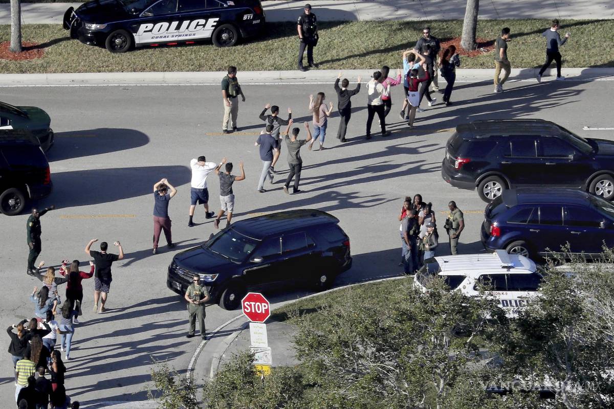 $!Varios estudiantes levantan los brazos mientras son evacuados por la policía de la escuela secundaria Marjory Stoneman Douglas en Parkland, Florida.