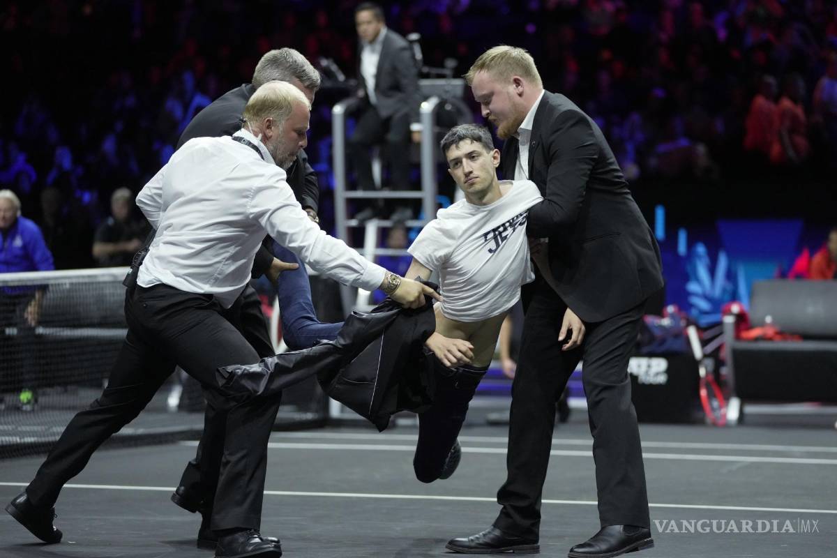 $!La seguridad se lleva a un hombre después de que se prendiera fuego en su brazo durante una protesta en el O2 de Londres.