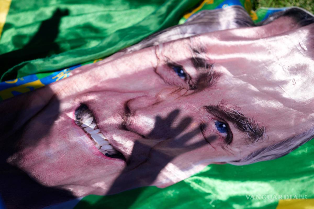 $!La sombra de un simpatizante del expresidente Jair Bolsonaro se proyecta sobre una imagen suya expuesta fuera del hospital donde fue trasladado de prisión para cirugía, en Brasilia, Brasil, el 24 de diciembre de 2025. (Foto AP/Eraldo Peres)