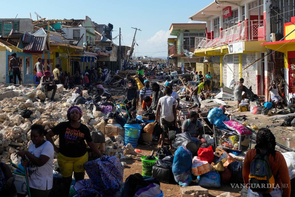 $!Residentes, entre los escombros causados por el paso del huracán Melissa por una calle de Black River, Jamaica.