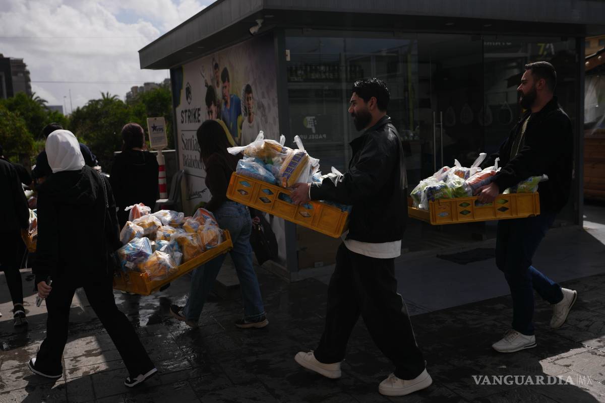 $!Voluntarios transportan paquetes de alimentos para familias desplazadas que viven en una universidad pública convertida en refugio en Beirut, Líbano