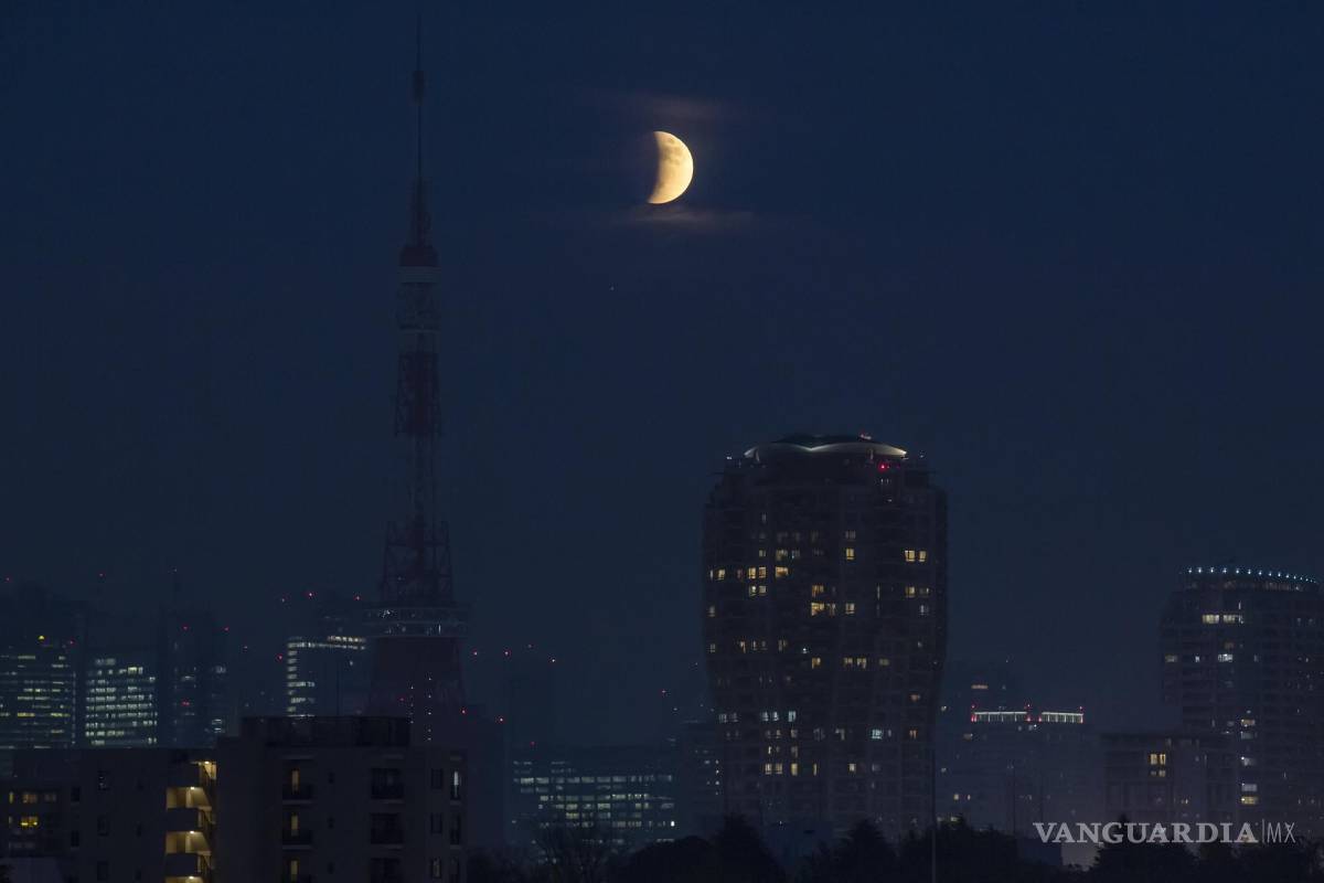 $!Un eclipse lunar parcial sobre la Torre de Tokio se asoma detrás de las nubes en Tokio. AP/Kiichiro Sato